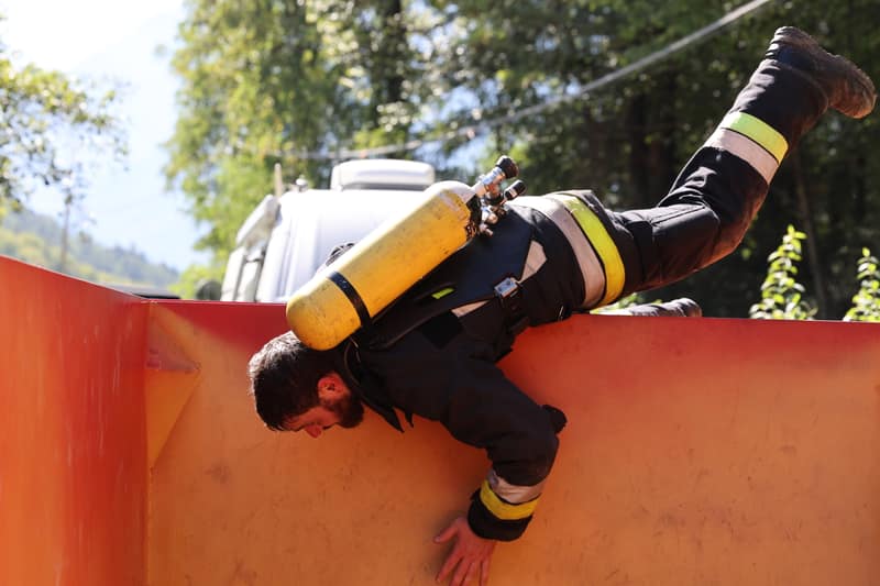 Feuerwehrmann in voller Montur klettert über den Container